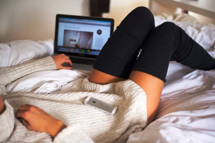 mujer en la cama y laptop ve peliculas