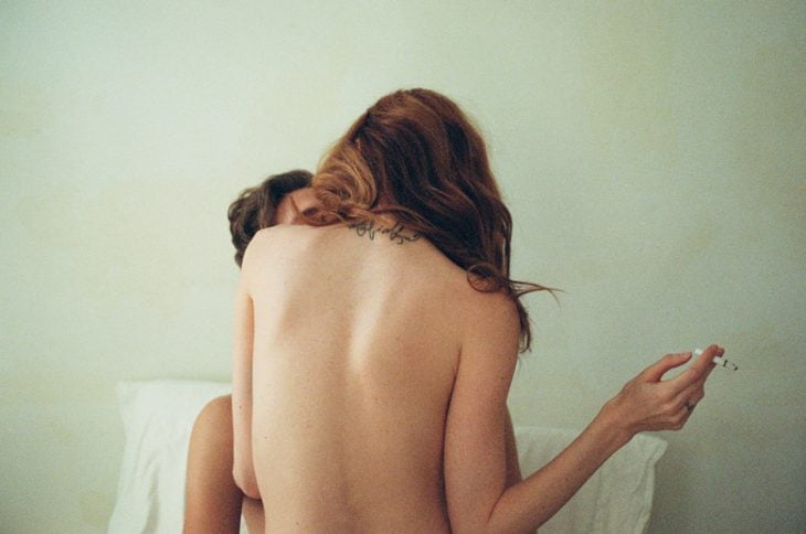 pareja besandose en la cama mujer de espaldas