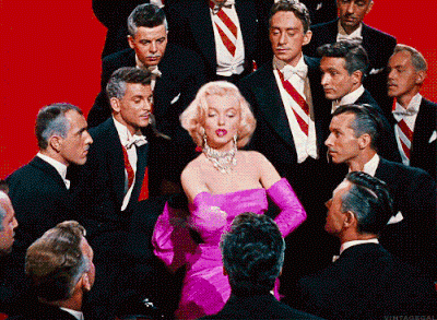 Marilyn monroe rodeada de hombres mientras les pega con un abanico 