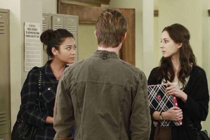 Escena de la serie pretty little liars chicas hablando con un chico en le pasillo 