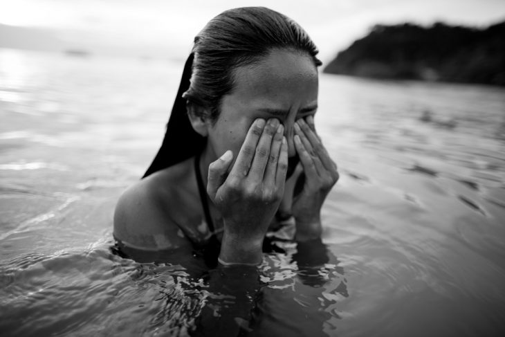 Chica en el agua tallando los ojos 