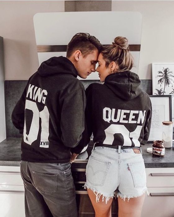 Pareja de novios usando sudaderas que dicen king y queen 