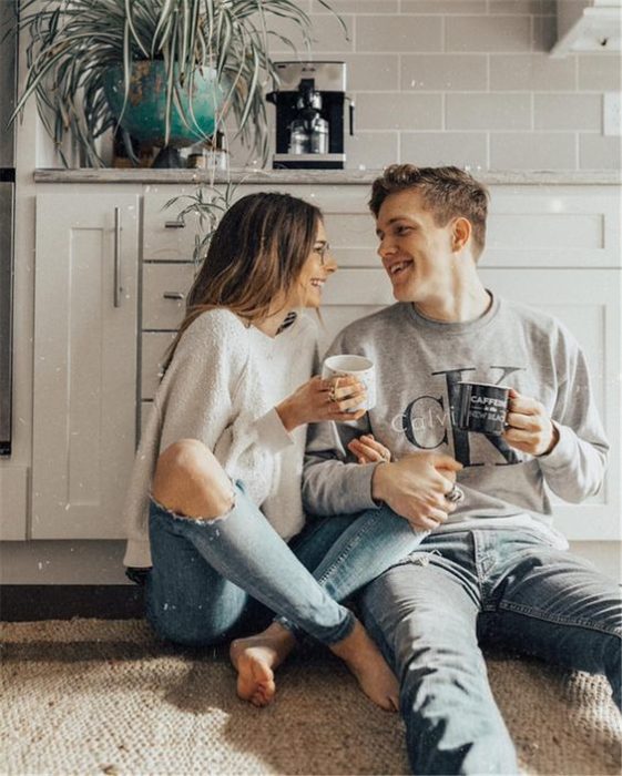 Pareja de novios sentados en la cocina tomando café mientras conversan 