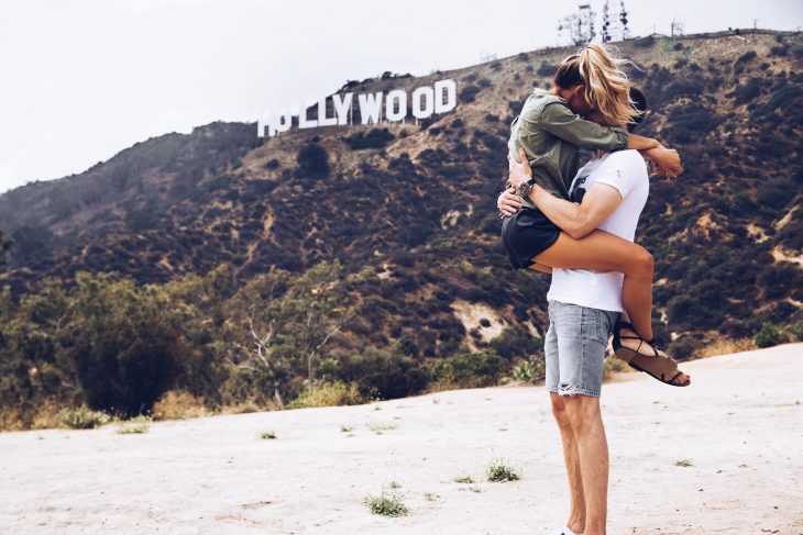 Pareja de novios besándose frente al letrero de Hollywood 