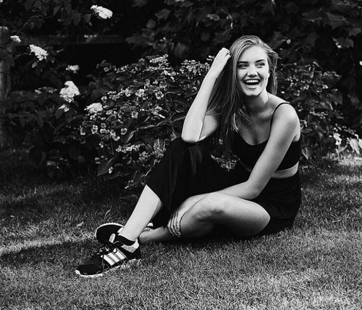 Chica sentada en el pasto sonriendo 