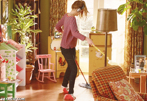 Chica limpiando su casa mientras está bailando 