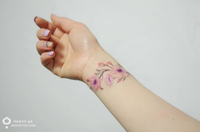 Tatuaje de acuarela en forma de flores rosas colocadas en la muñeca