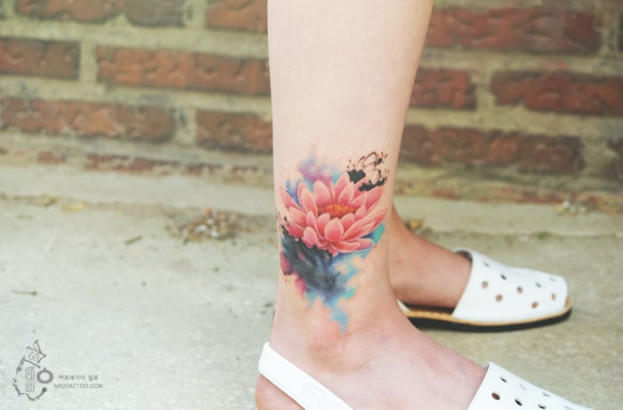 Tatuaje de acuarela en forma de flor colocado en la pantorrila 
