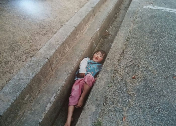 Kotori Kawashima fotografiando a una niña mientras está atorada entre la acera y la calle 