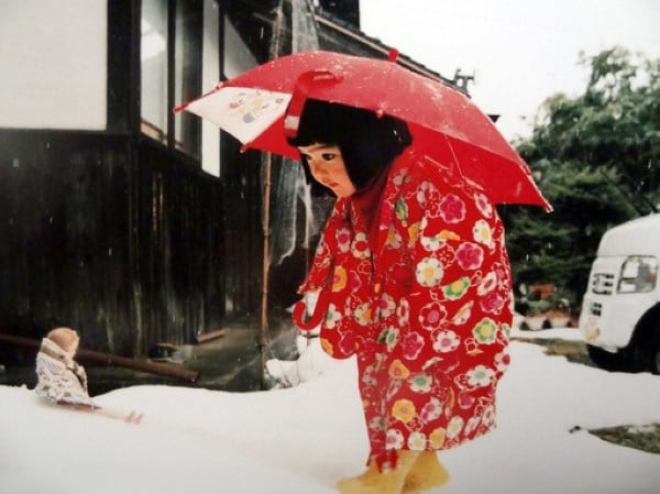 Kotori Kawashima fotografiando a una niña mientras está sujetando un paraguas 