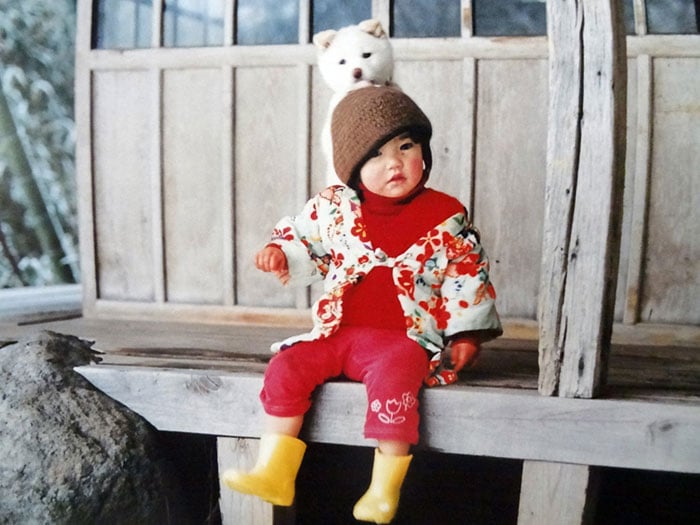 Kotori Kawashima fotografiando a una niña mientras está sentada junto a un perro 
