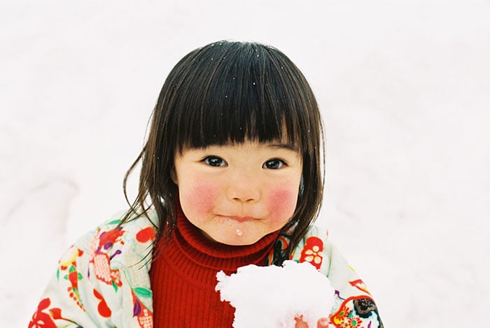 Kotori Kawashima fotografiando a una niña mientras tiene un copo de nieve en sus manos 