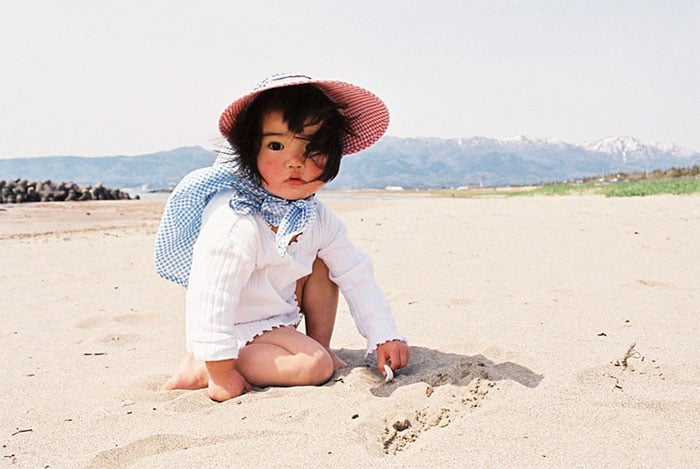 Kotori Kawashima fotografiando a una niña mientras está en la playa 