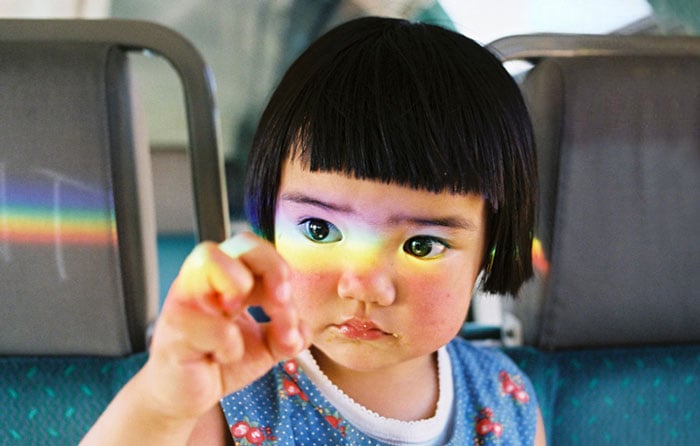 Kotori Kawashima fotografiando a una niña mientras un arco iris se refleja en su cara