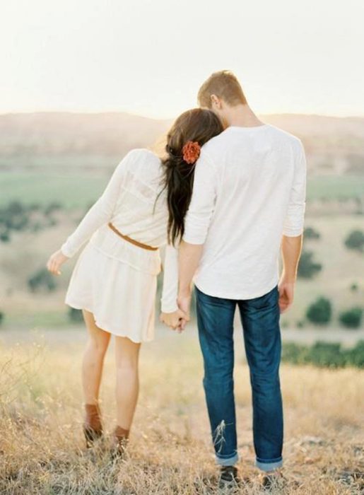 Pareja de novios tomados de las manos viendo el atardecer 