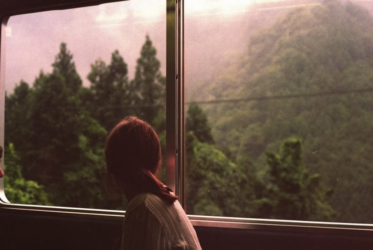 Chica viajando en bus viendo por la ventana 