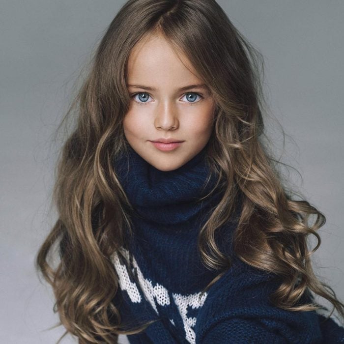Kristina Pimenova la niña más bonita del mundo posando para una sesión de fotografías usando un suéter de color azul 