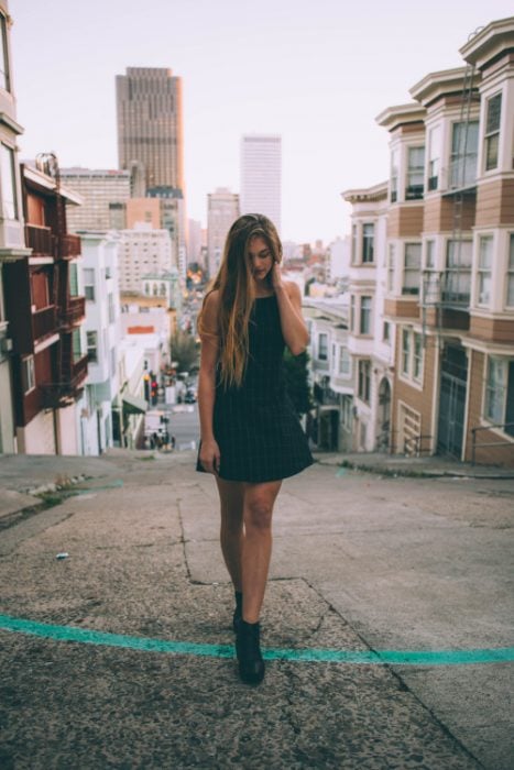 Chica con vestido negro caminando en la calle 