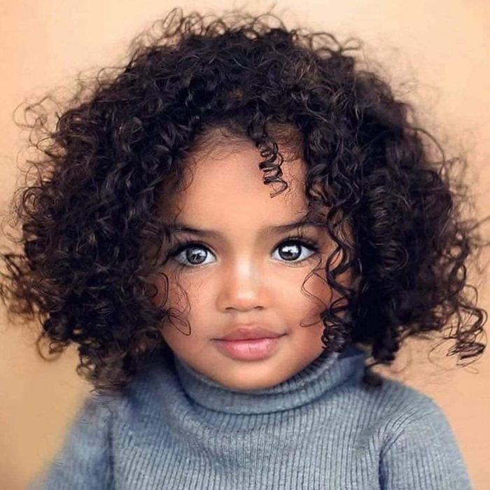 Niña pequeña morena con cabello muy rizado y ojos claros