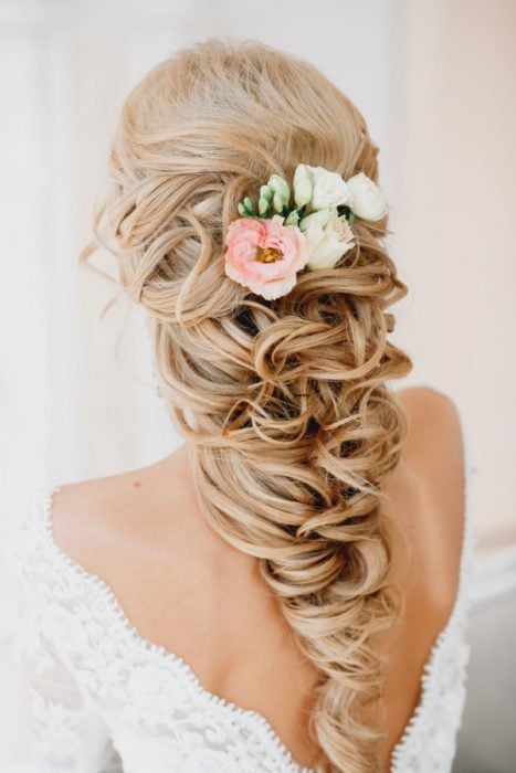 Peinados para el día de tu boda, chica usando un peinado suelto con chinos y accesorios de rosas 