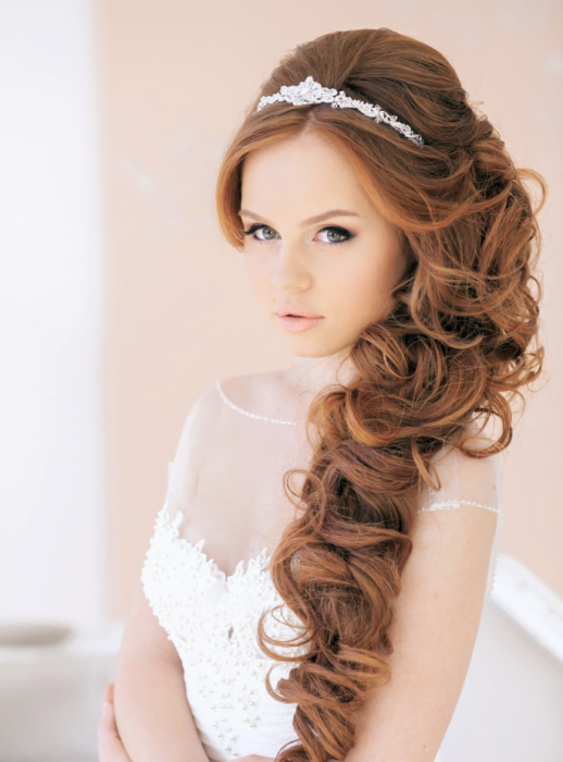 Peinados para el día de tu boda, chica usando el pelo en rulos de lado junto con una tiara 