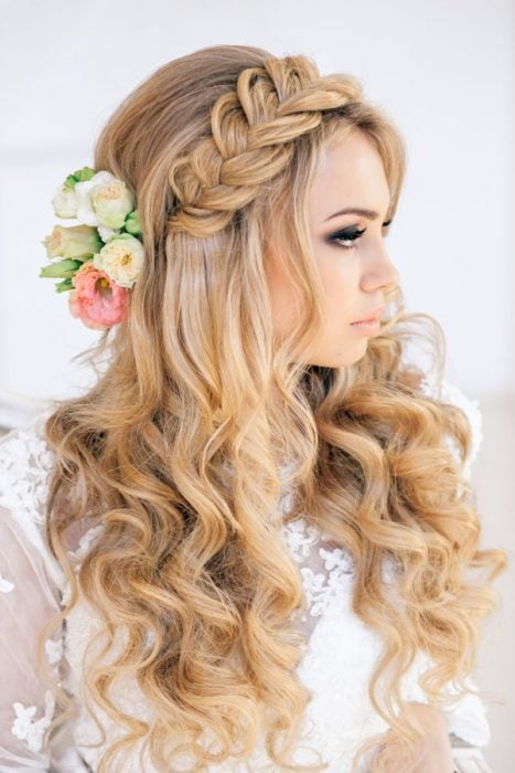 Peinados para el día de tu boda, chica usando el cabello suelto y chino con una trenza y flores como accesorios 