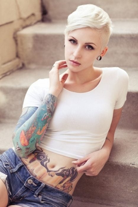 Chica rubia con tatuajes y el cabello rapado 