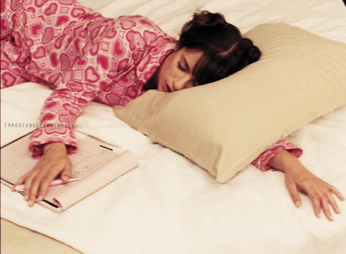 GIF chica recostada en la cama durmiendo mientras sostiene un libro 