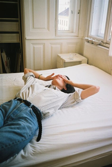 Chica vestida con vaqueros y camisa durmiendo sobre la cama 