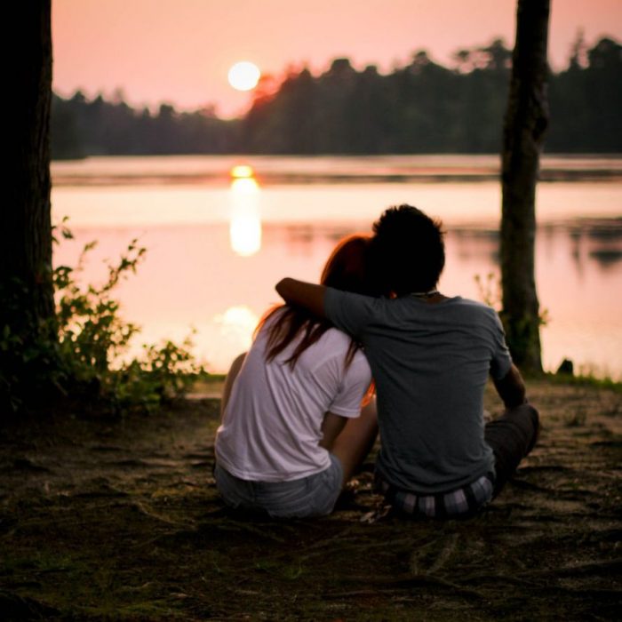 pareja sentados frente a un lago