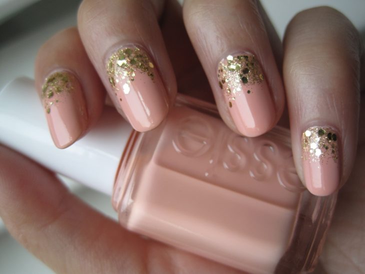 Uñas pintadas en color nude con brillos dorados 