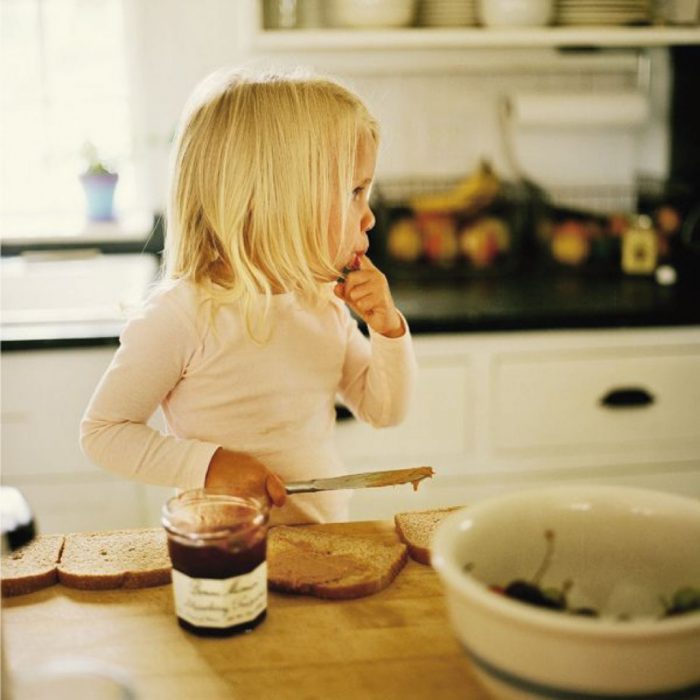 niña comiendo pan y nutella en la cocina 