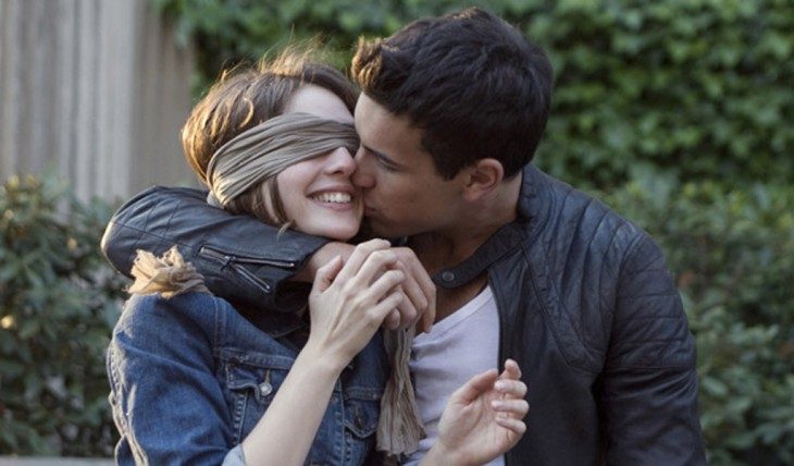 pareja chica con ojos vendados sonrie feliz y el la besa 