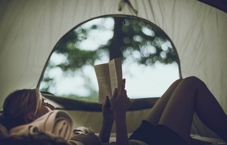 chica acostada leyendo un libro en el bosque casa de acampar 