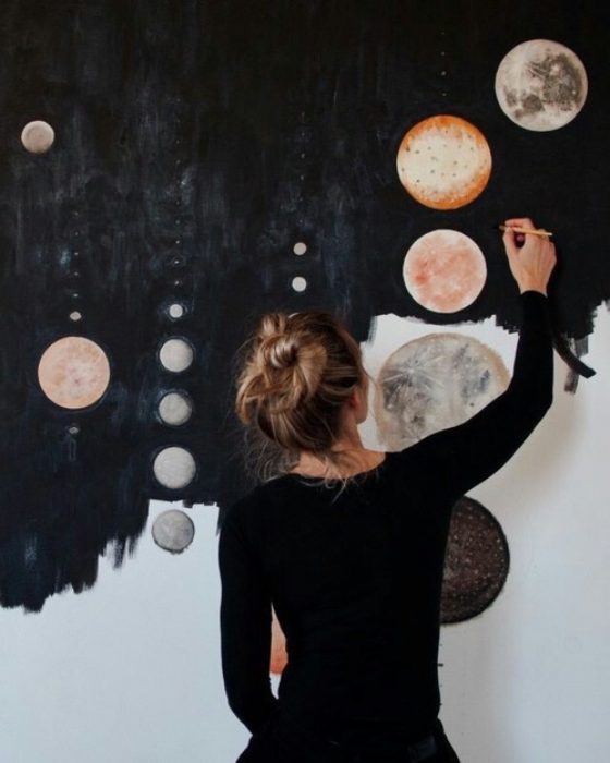 mujer pintando en la pared galaxia y planetas artista 