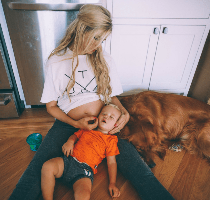 mama embarazada con hijo en las piernas y perro dormido cocina