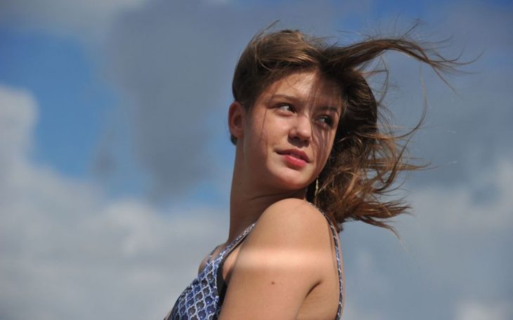 chica linda sonrie con cabello volando en el viento