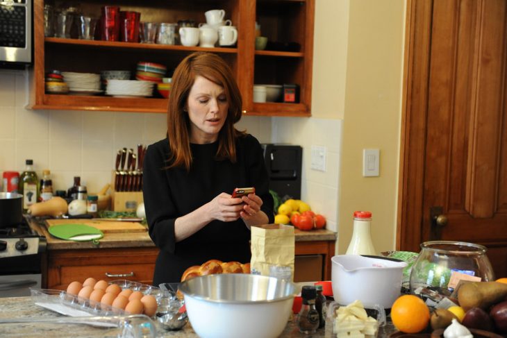 mujer pelirroja en la cocina viendo su celular 