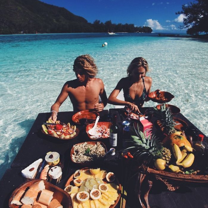 pareja comiendo frutas en la playa