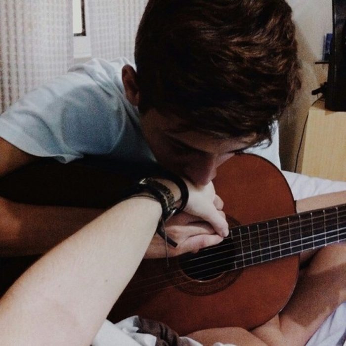 hombre besando la mano de su novia mientras toca la guitarra