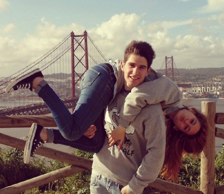 chico cargando a su novia con puente atras paisaje 