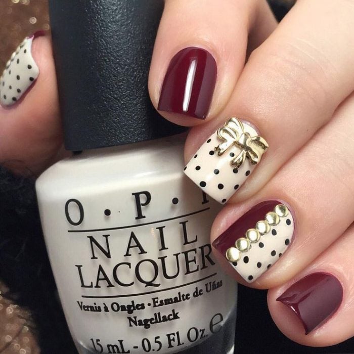 Uñas decoraas en color ciruela y blanco con puntos negros y dorados