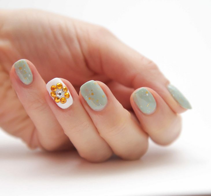 Uñas decoradas en color verde menta con un oso amarillo