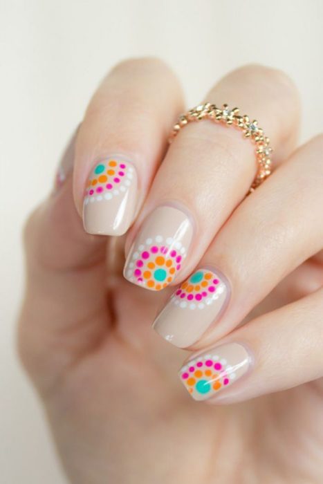 Uñas decoradas en color nude con puntos rosas y naranjas 