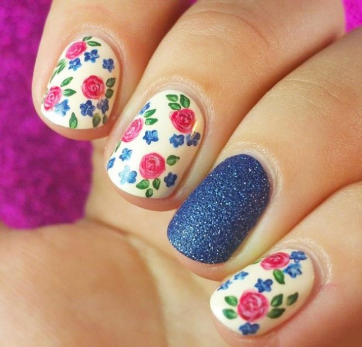 Uñas decoadas con rosas rosas y una uña color azul 