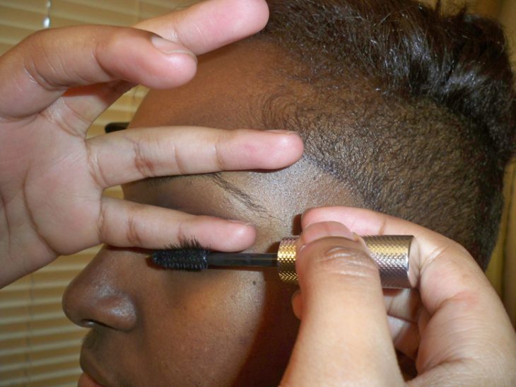 mujer rizando y aplicando mascara en las pestañas 