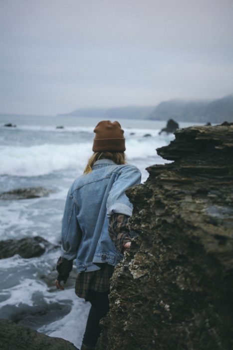 chica caminando entre rocas en la playa