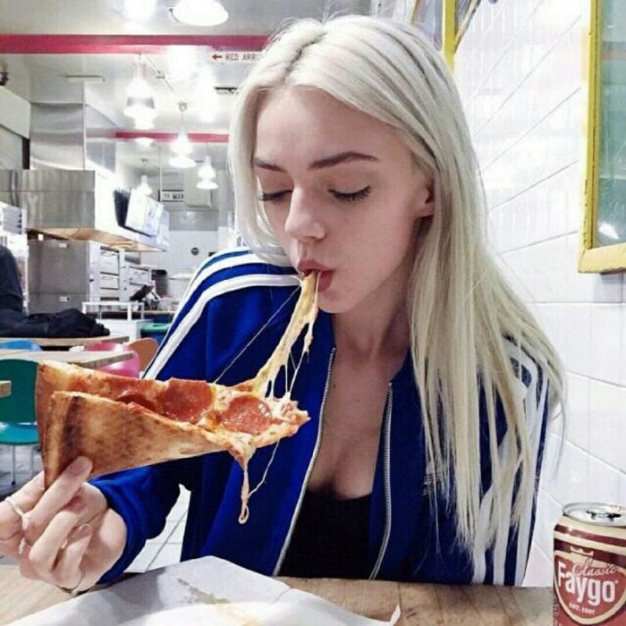 Chica comiendo un gran trozo de pizza 