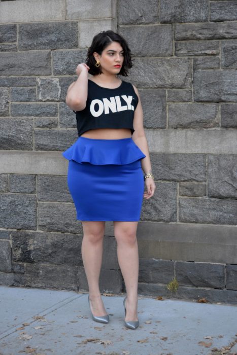 Chica curvi usando un crop top en color negro con una falda en color azul 