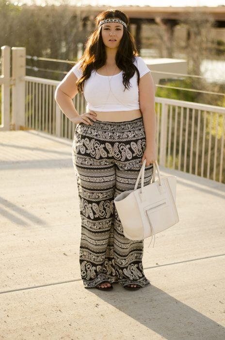 Chica curvi usando un crop top en color blanco con un pantalón con estampados